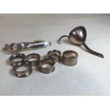 Six silver napkin rings, hallmarked. Total weight 98gm. Also with a white metal wine funnel and