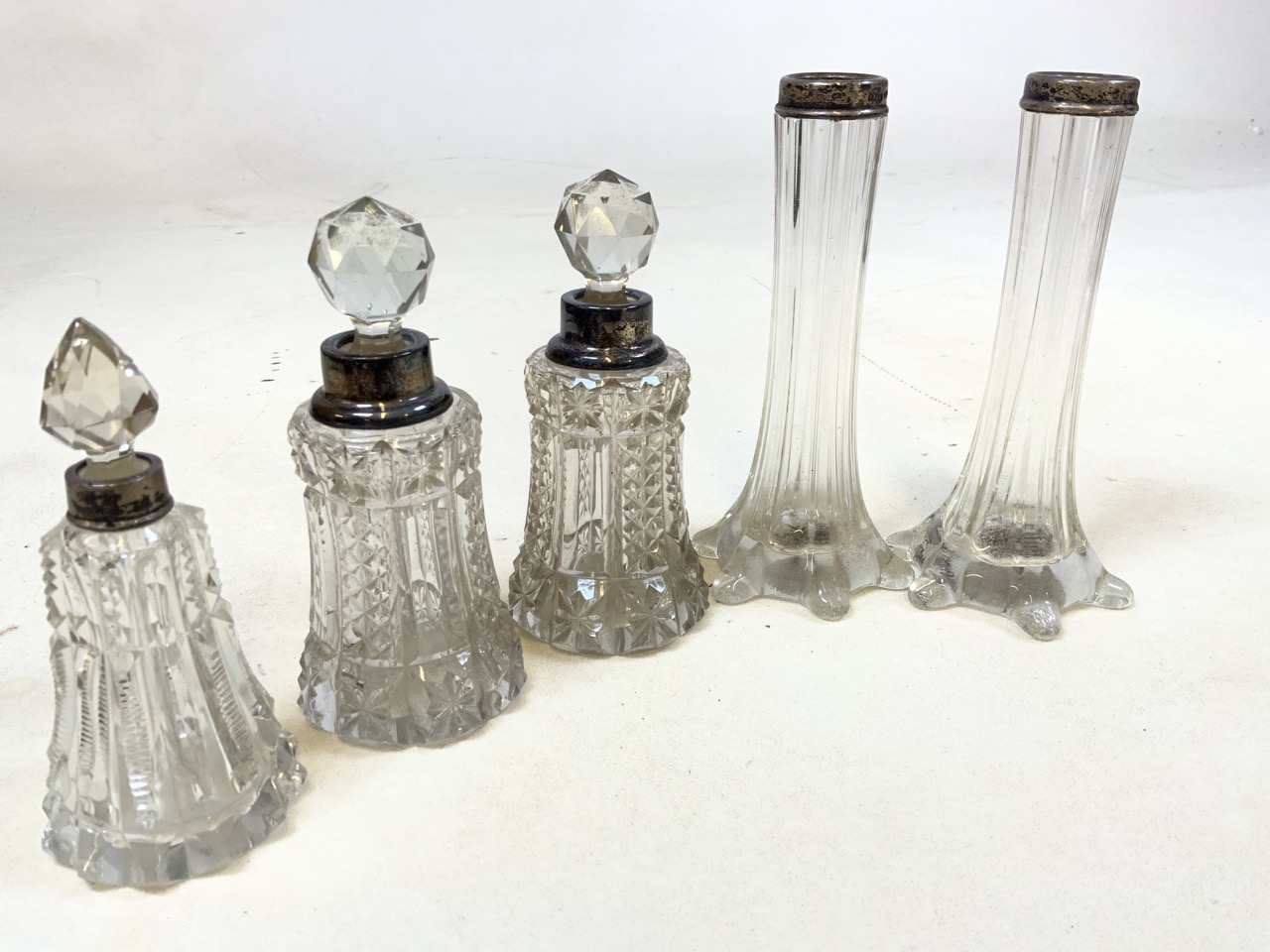 Three Silver topped cut glass scent bottles also with a pair of silver topped vases.