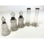 Three Silver topped cut glass scent bottles also with a pair of silver topped vases.