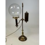 An early 20th century adjustable stundents lamp with glass shade, later wired for electric.