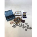 A quantity of commemorative crowns and other coins and notes on a vintage cash box