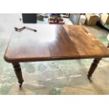 A small early 20th century mahogany dining table on large brass and ceramic castors with extra