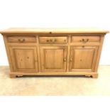 A modern solid pine sideboard with three drawers above cupboards. With brass handles. W:168cm x D: