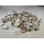 A large collection of crested ware including a Teepee, a donkey, a tank, a helmet a yacht and