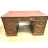 An early 20th century oak leather topped pedestal desk with nine drawers with brass handles. W:138cm