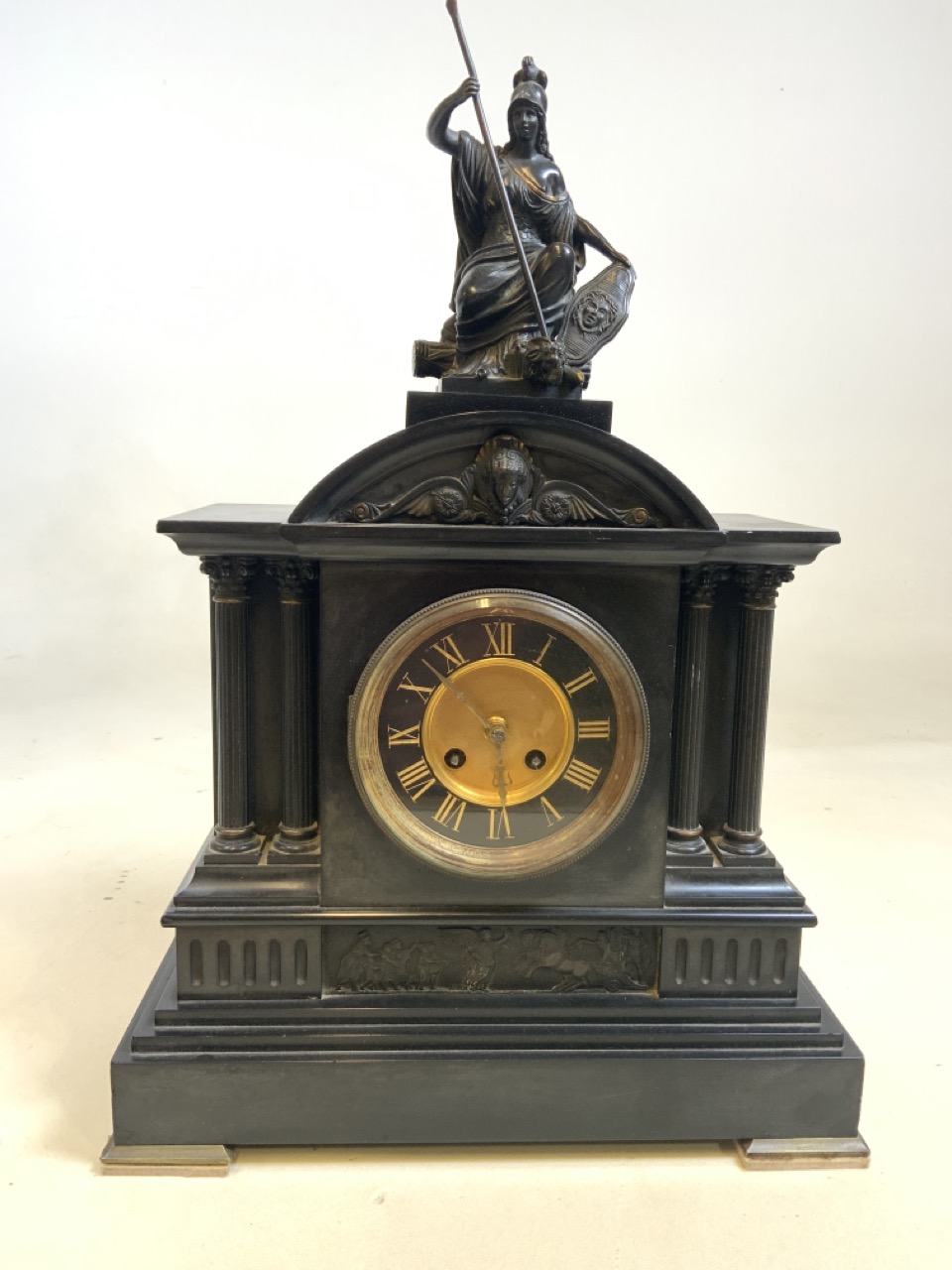 A large slate black and gilt mantle clock with Ionic columns and Greek figural scenes with Statue of