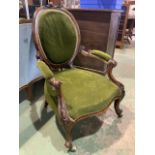 An upholstered Victorian arm chair with scroll carved arms. On ceramic and brass castors. H:35cm