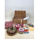 A wicker hamper with a quantity of sewing items