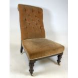 A Late Victorian button and scroll back nursing chair with turned legs and brass and ceramic