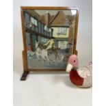 An Art Deco oak fire screen with tapestry scene of a huntsman and dog also with a duck door stop.