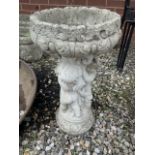 A reconstituted stoneware bird bath with three cherub support. W:36cm x D:36cm x H:64cm