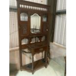 An early 20th century hall stand with carved panels, central shield shaped mirror, six brass