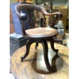 A Victorian revolving captains chair with leather seat on small brass castors. With scroll arms