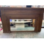 A large architectural style solid oak overmantle mirror with wide bevel. W:164cm x D:9.5cm x H:95cm