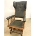 An antique wing back rocking chair with leather upholstery, castors to the front. W:57cm x D:67cm