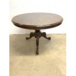 A circular breakfast tilt top table on turned column and tripod base with metal castors. W:104cm x
