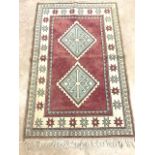 A vintage Turkish rug with two diamond medallions on red ground surrounded by creams and blue