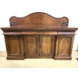 A breakfront flame mahogany sideboard with three top drawers above cupboards. With carved scroll