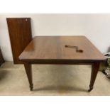 An early 20th century mahogany extending dining table on tapered legs with large brass castors. With