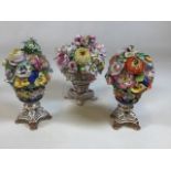 Three pieces of Bloor Derby Porcelain floral urns. Two are 18cm high and one is 20cm high. Some