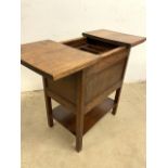 An early 20th century sewing table with sliding open top to an oak sectioned tray and cupboard