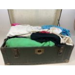 A vintage suitcase full of fabrics and clothing.