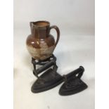 A silver rimmed Lambeth Doulton jug with a cast iron trivet and 2 flat irons