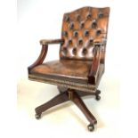 A good quality Norweigan brown leather button backed office swivel chair, with studded finish on