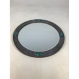 An Arts and Crafts circular pewter mirror. Frame mounted with four turquoise ceramic cabochons,