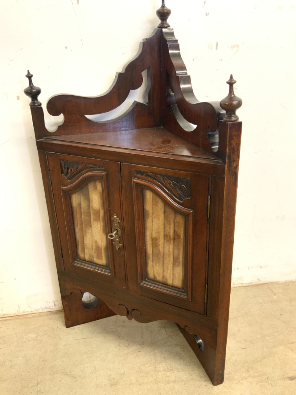 A small early 20th century wall hanging corner cupboard with glazed doors and a working key also