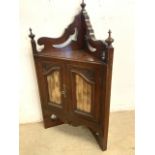 A small early 20th century wall hanging corner cupboard with glazed doors and a working key also