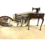 A Vickers sewing machine in fitted table, with three frameless mirrors and another.