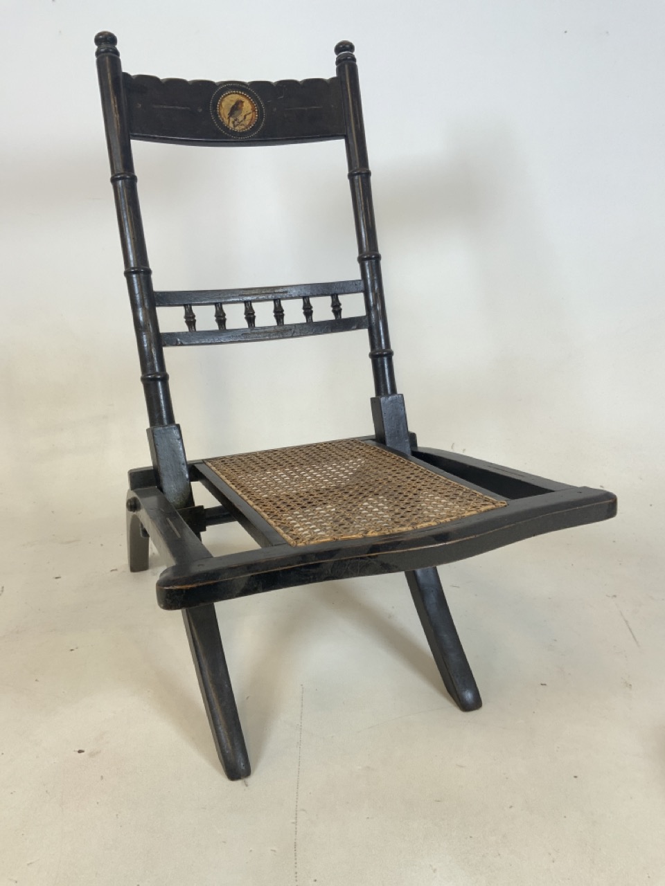 A Late 19th century folding rattan childs or nursing chair with bird illustration in circular