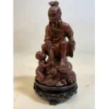 A Carved Chinese figure with stone eyes on circular carved plinth. H:27cm