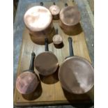 Seven French copper sauce pans on pine display board.