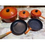 Le Creuset lidded pots and frying pans.