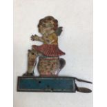 A German tin plate lithographed clicker toy of a girl sitting on a potty, a rat appears when she