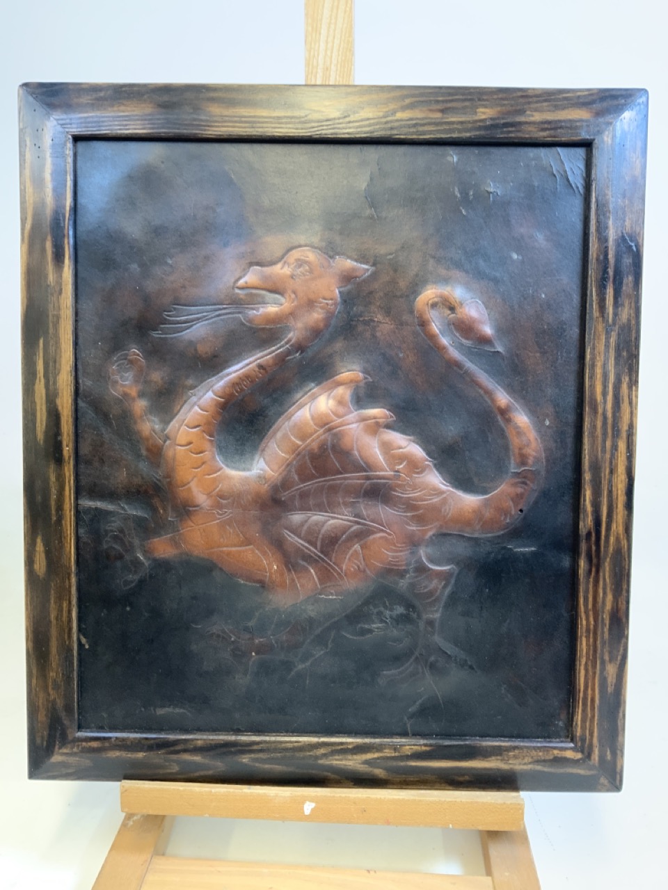 An antique framed leather panel of a dragon. W:38cm x H:45cm