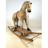 A Vintage animal hide rocking horse with rocker or on wheels.