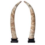 A pair of monumental faux-tusk, assembled from carved bone, on a wooden base, Total H 166 cm