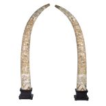 A pair of monumental faux-tusk, assembled from carved bone, on a wooden base, Total H 233,5 cm