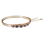 (T) An 18ct yellow gold bracelet, set with ten small diamonds and five sapphires, inner ø 5,8 cm, to