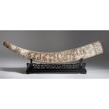 A faux-tusk, assembled from carved bone, on a wooden base, L cm