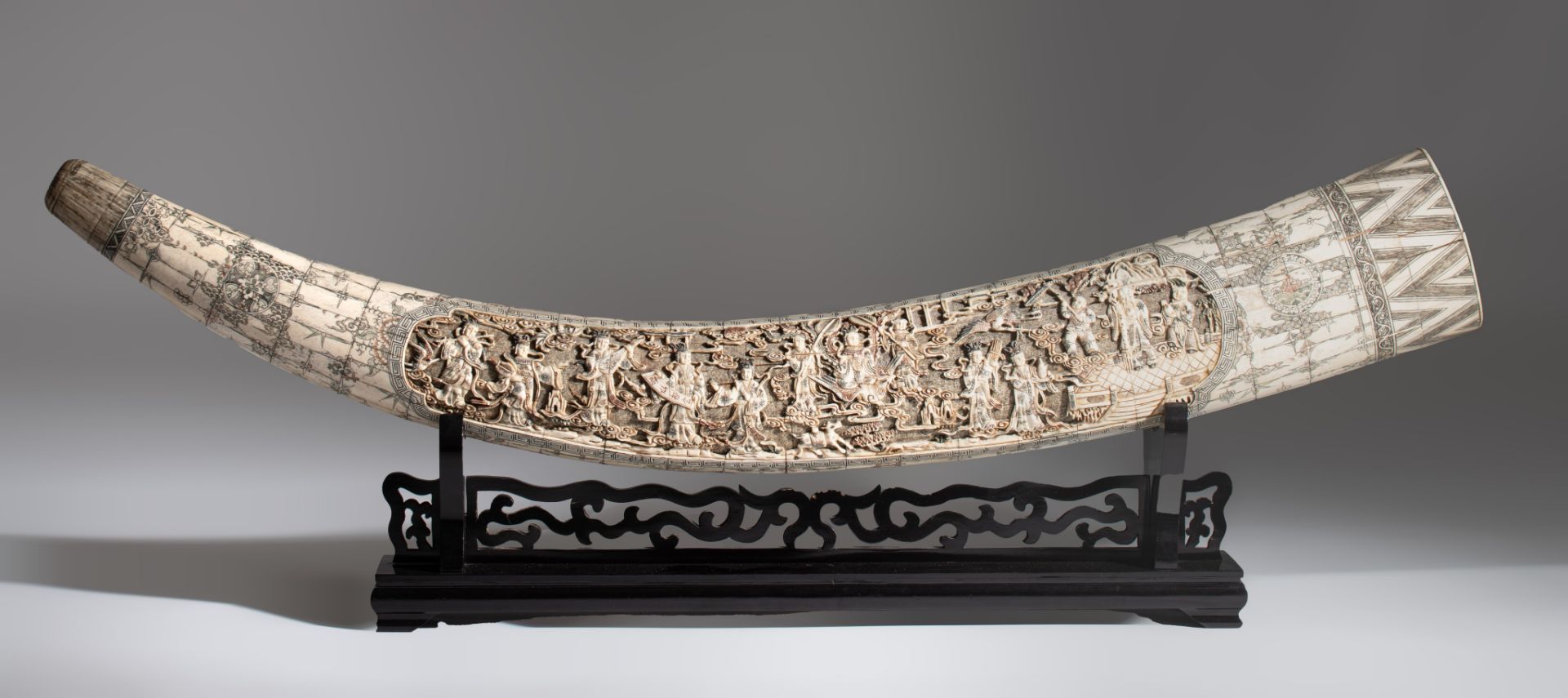 A faux-tusk, assembled from carved bone, on a wooden base, L cm