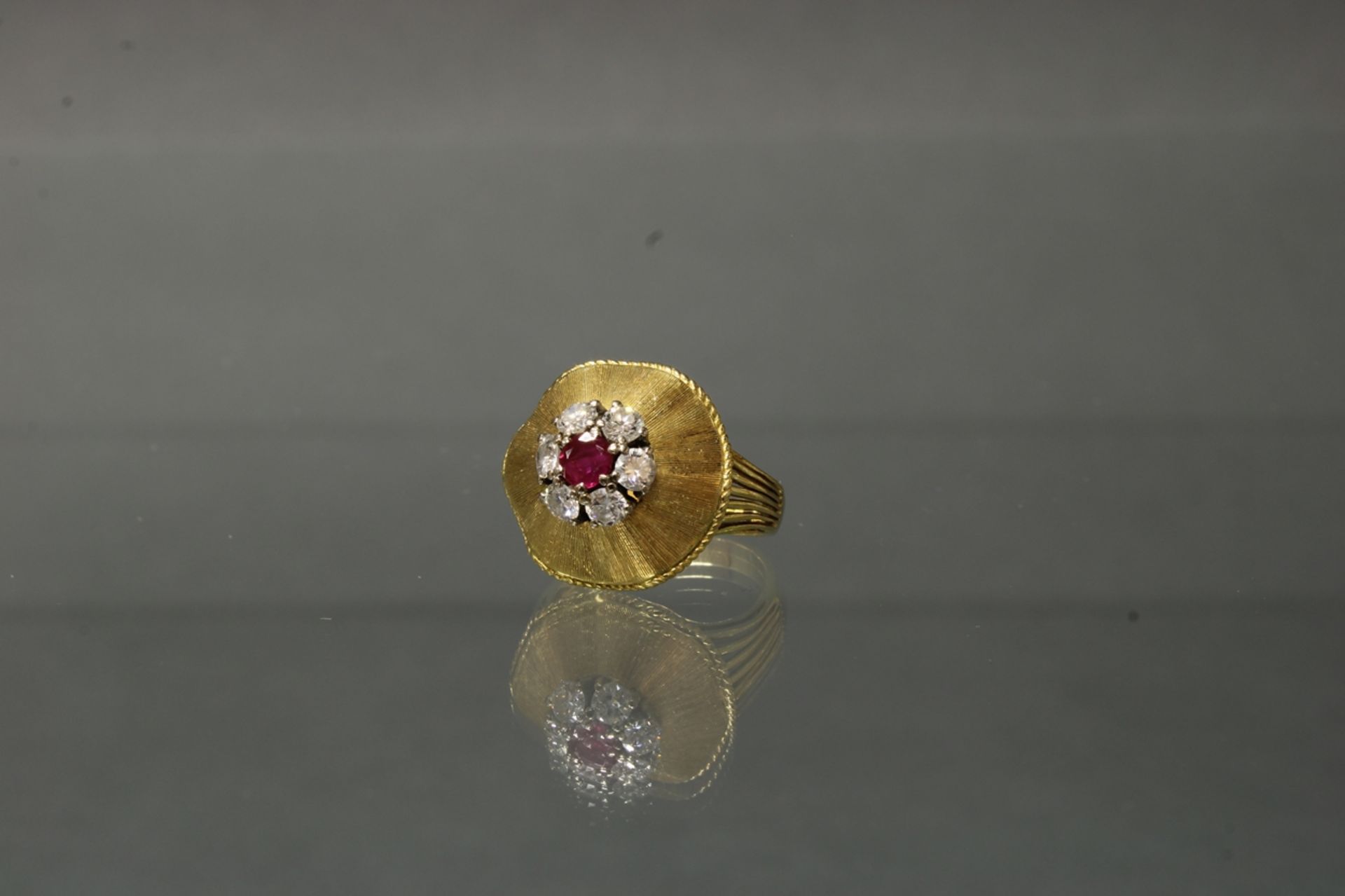 Ring, 1960er Jahre, GG 750, Blütenform, 1 runder facettierter Rubin, 6 Brillanten zus. ca. 0.60 ct.