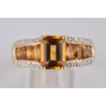 Ring, GG 585. 1 Citrin im Smaragdschliff, 8 Citrine im Ovalschliff, 20 kleine Diamanten zus. ca. 0.