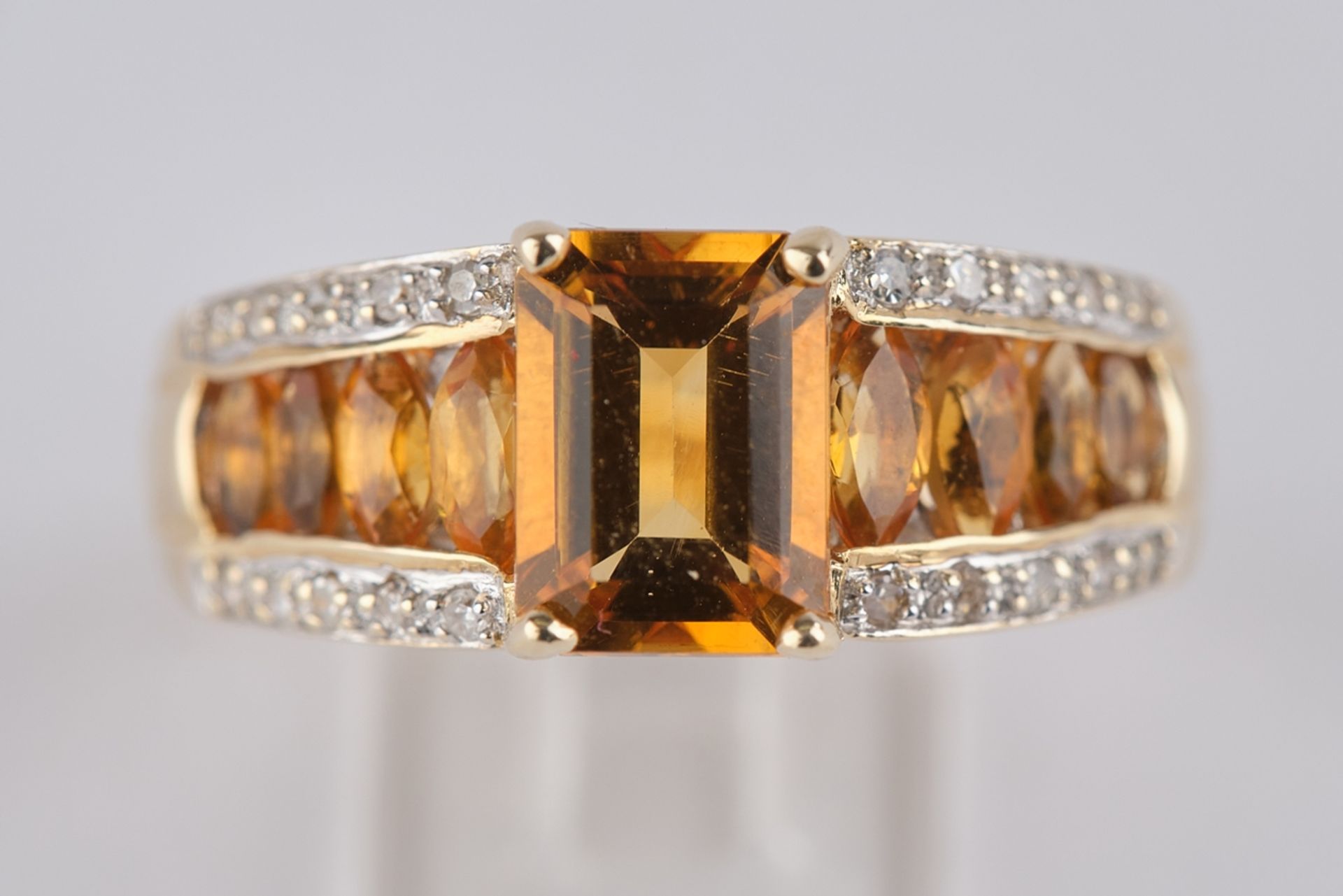 Ring, GG 585. 1 Citrin im Smaragdschliff, 8 Citrine im Ovalschliff, 20 kleine Diamanten zus. ca. 0.