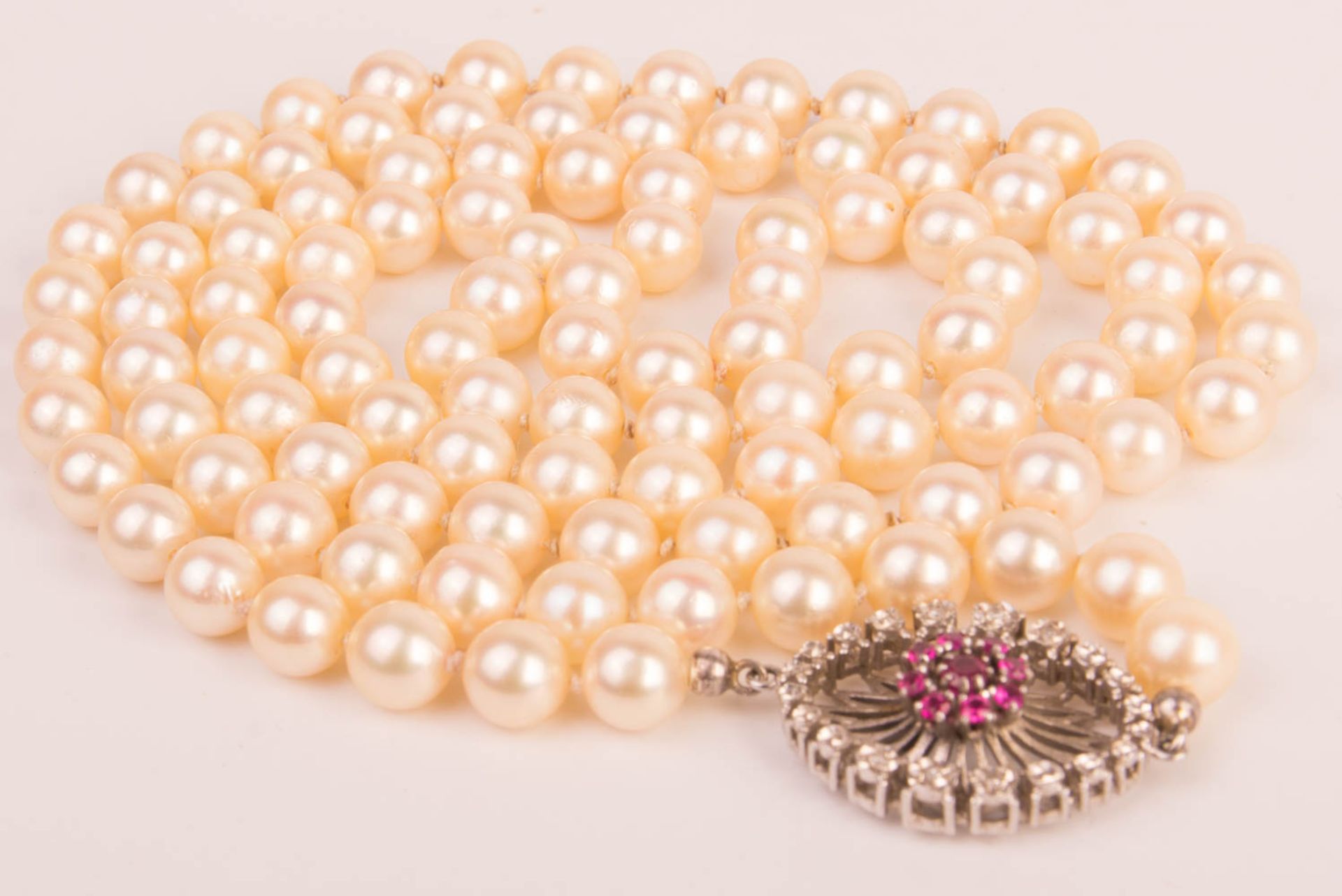 Long pearl necklace with rubies and precious stones.