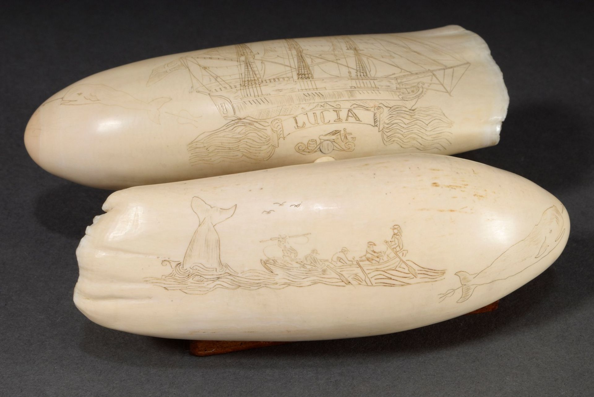 2 Scrimshaws „Lucia“, verbunden und auf Holzsockel montiert, Walzahn mit gefärbtem Ritzdekor „3-Mas