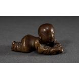 Kleine chinesische Gelbguss Figur "Liegendes Kind", dunkel patiniert, H. 2cm, L. 4cm